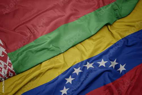 waving colorful flag of venezuela and national flag of belarus.