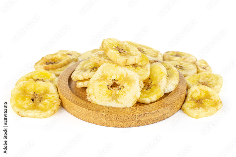 Lot of slices of sweet yellow dry banana on bamboo coaster isolated on white background