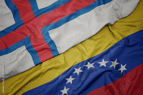 waving colorful flag of venezuela and national flag of faroe islands.