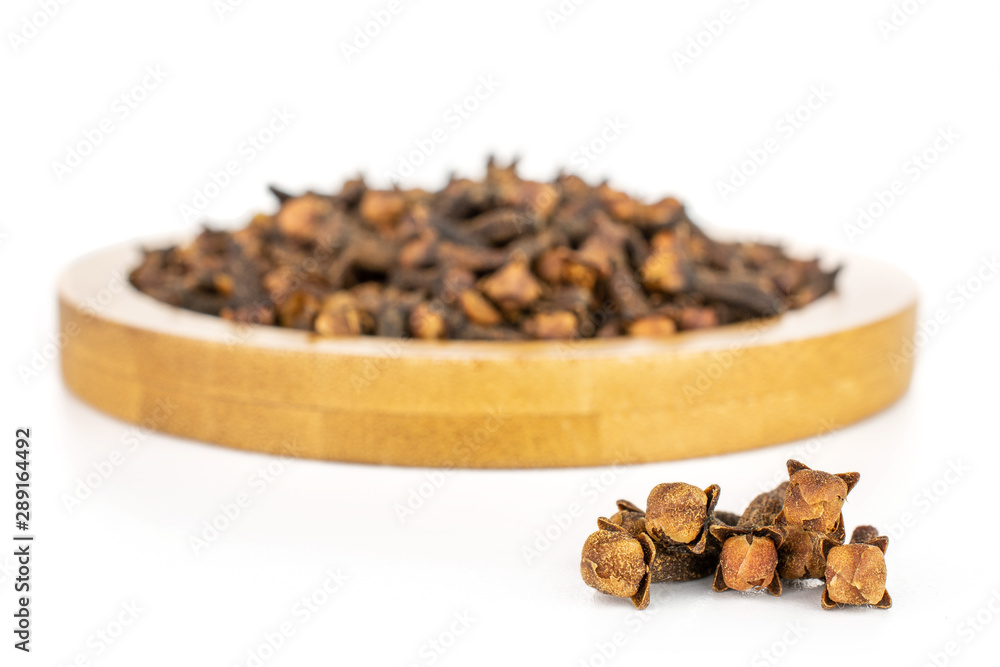 Lot of whole dry brown clove on bamboo coaster isolated on white background