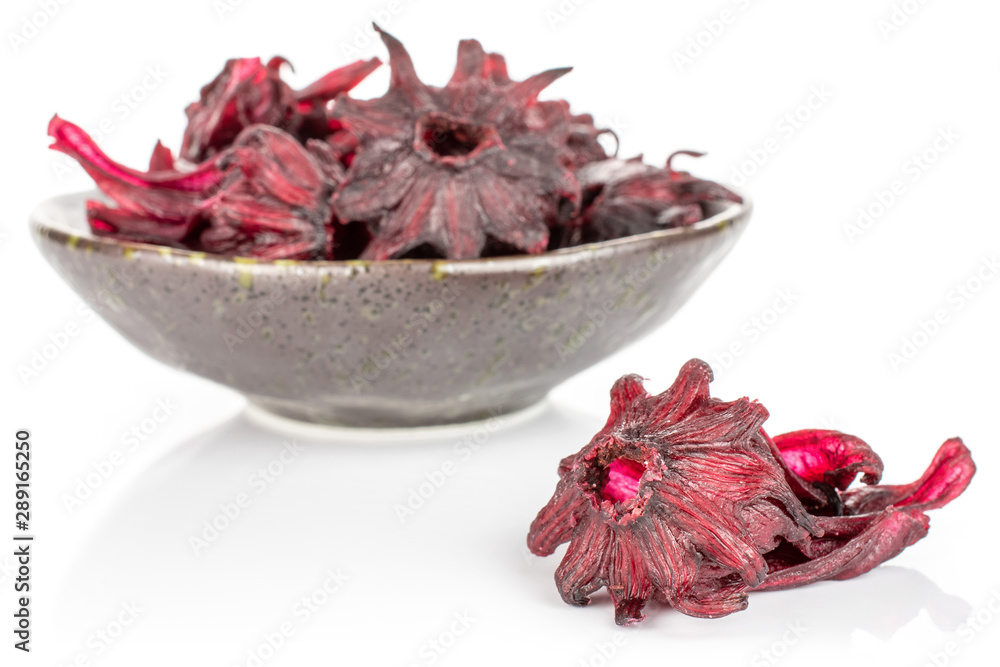 Lot of whole sweet red candied hibiscus in dark ceramic bowl isolated on white background Lot of whole sweet red candied hibiscus in dark ceramic bowl isolated on white background