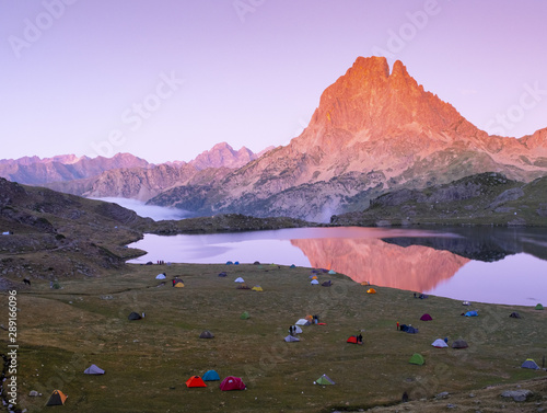 Camping tents on Lake Gentau at night with Mount Midi d'Ossau reflected on the lake, France