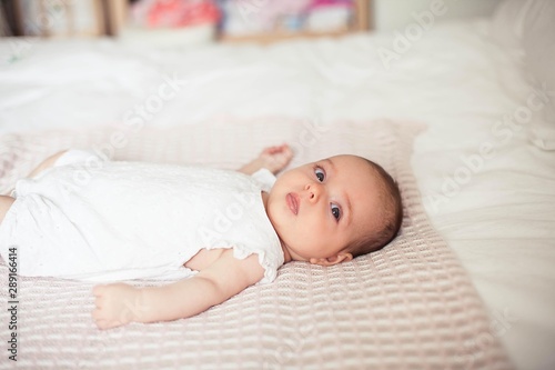 Little cute girl 3 months old is lying on the bed. Baby. Children bedroom.