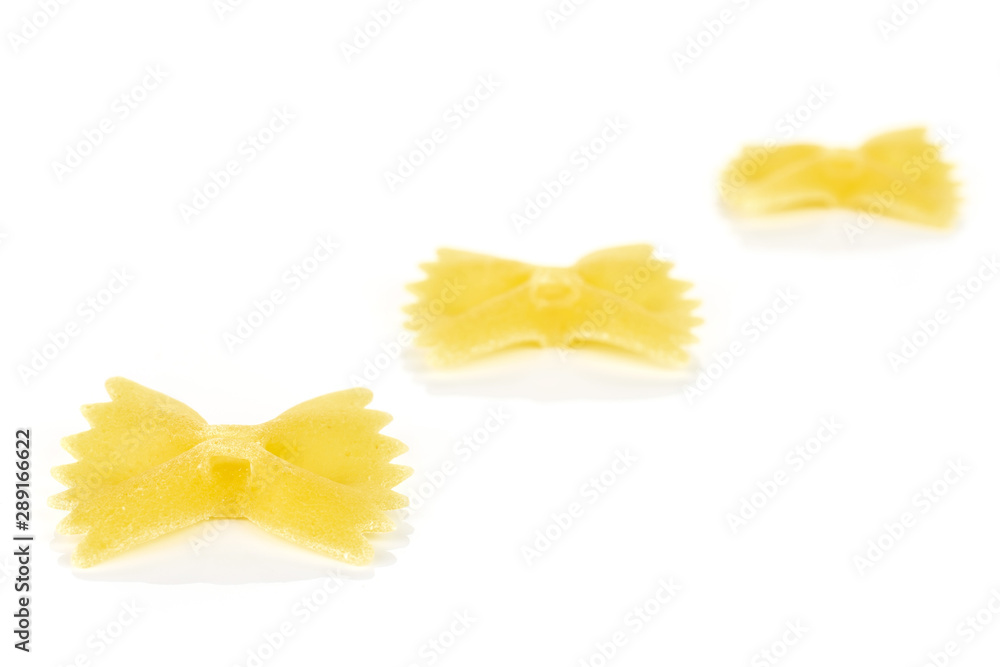 Group of three whole yellow uncooked farfalle isolated on white background Group of three whole yellow uncooked farfalle isolated on white background