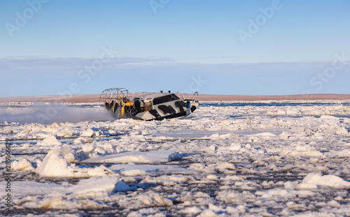 Airboat (air boat) crosses river estuary is covered by ice floes. Off-road transport, passenger and cargo transportation in the off-season in the Arctic. Anadyr estuary, Chukotka, Siberia, Russia.