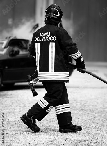 Foto firefighter with uniform and helmet and a broken car in italy