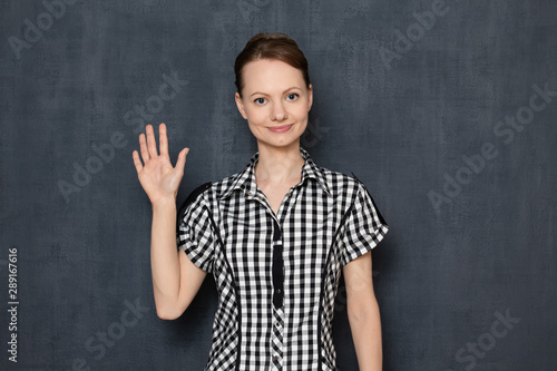Portrait of happy young woman waving her hand while greeting