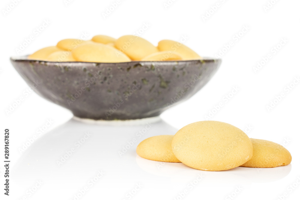 Lot of whole sweet golden sponge biscuit three are aside and the rest is in dark ceramic bowl isolated on white background Lot of whole sweet golden sponge biscuit three are aside and the rest is in dark ceramic bowl isolated on white background