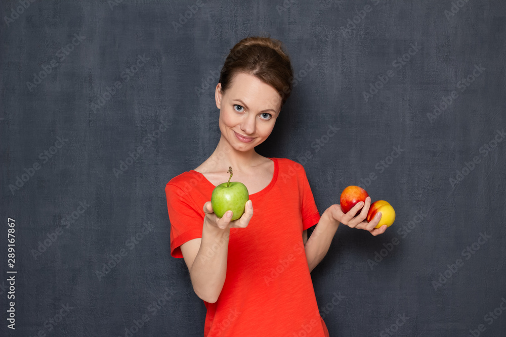 Portrait of happy young woman offering to taste ripe fruits Portrait of happy young woman offering to taste ripe fruits