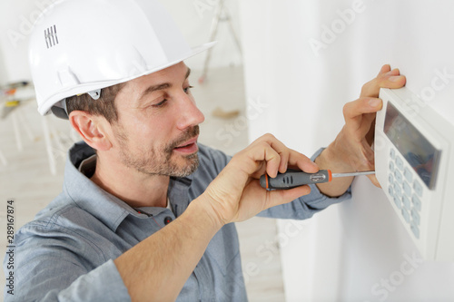 a happy plumber fixing thermostat