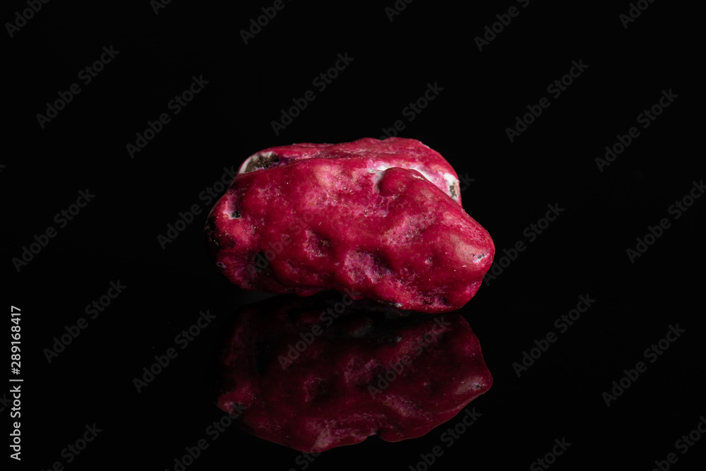 One whole purple sweet chocolate stone isolated on black glass One whole purple sweet chocolate stone isolated on black glass