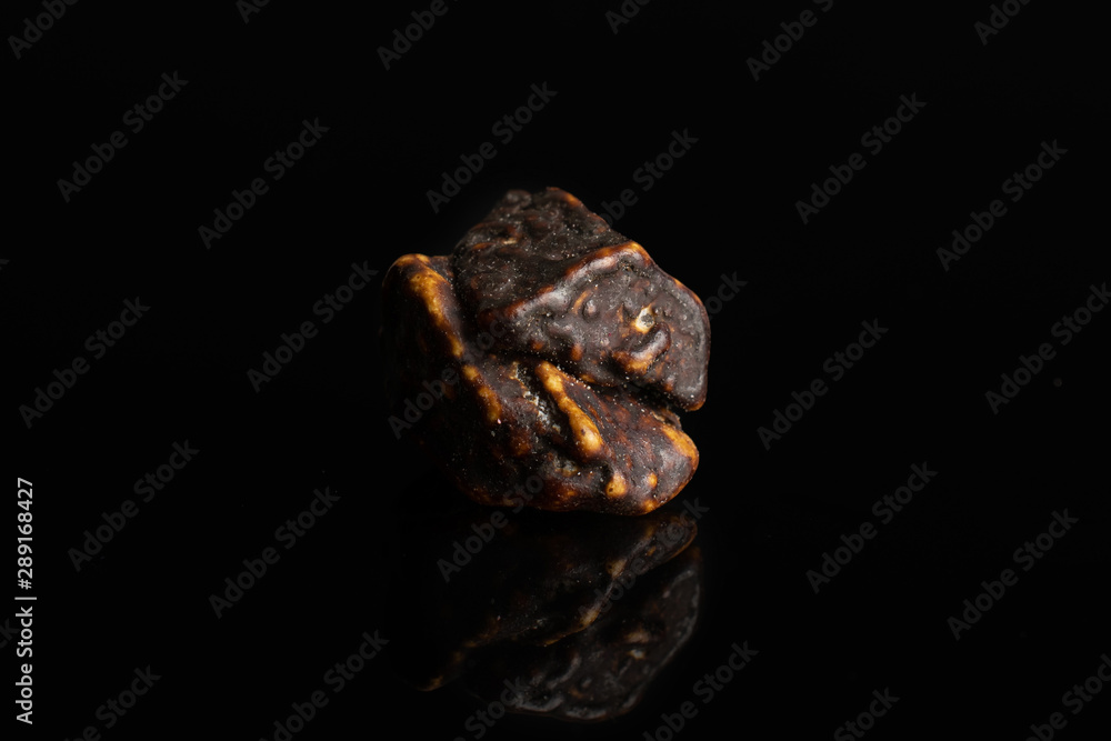 One whole dark brown sweet chocolate stone isolated on black glass One whole dark brown sweet chocolate stone isolated on black glass