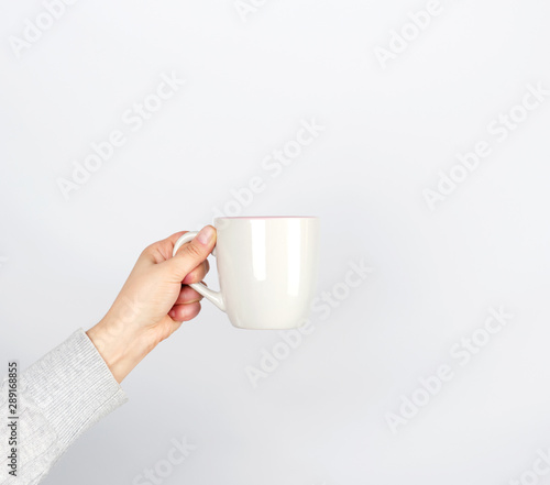 gray ceramic cup in female hand on a white background