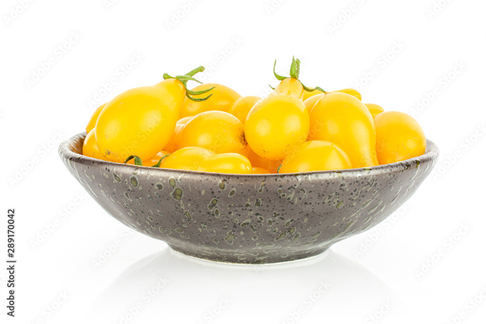 Lot of whole fresh yellow pear tomato in dark ceramic bowl isolated on white background Lot of whole fresh yellow pear tomato in dark ceramic bowl isolated on white background