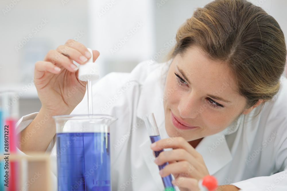 minded woman smiling while holding test tubes minded woman smiling while holding test tubes