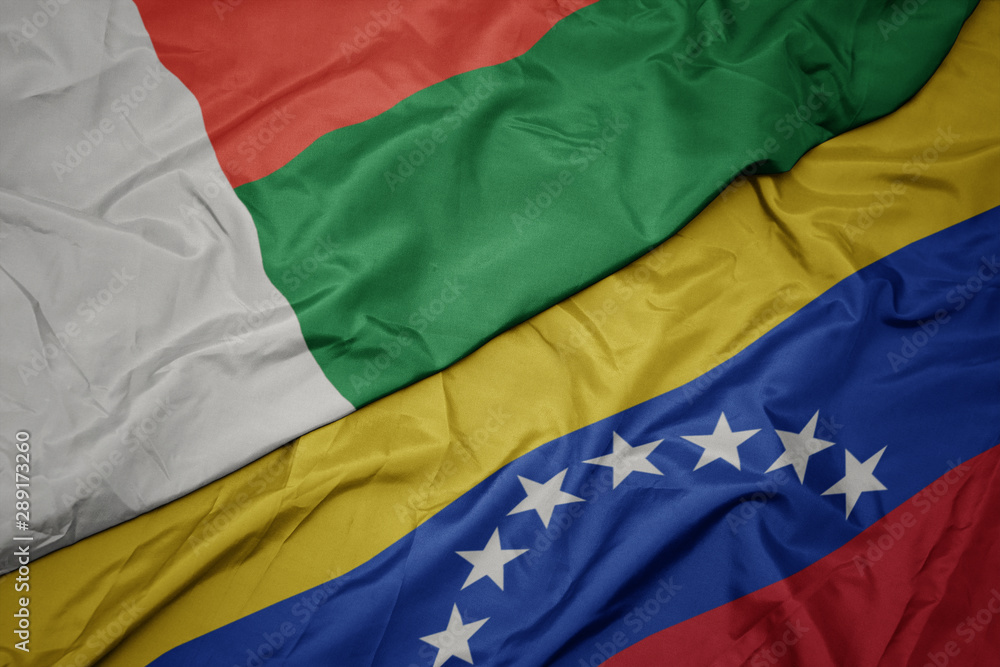 waving colorful flag of venezuela and national flag of madagascar. waving colorful flag of venezuela and national flag of madagascar.
