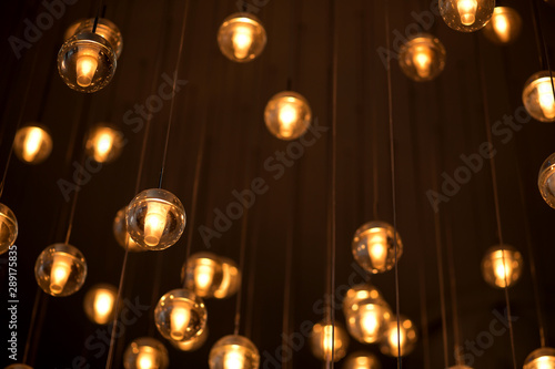 Decorated electric garland for lighting with bulbs warm white and yellow light on a dark background. Blurred background. Bulbs in the interior decor