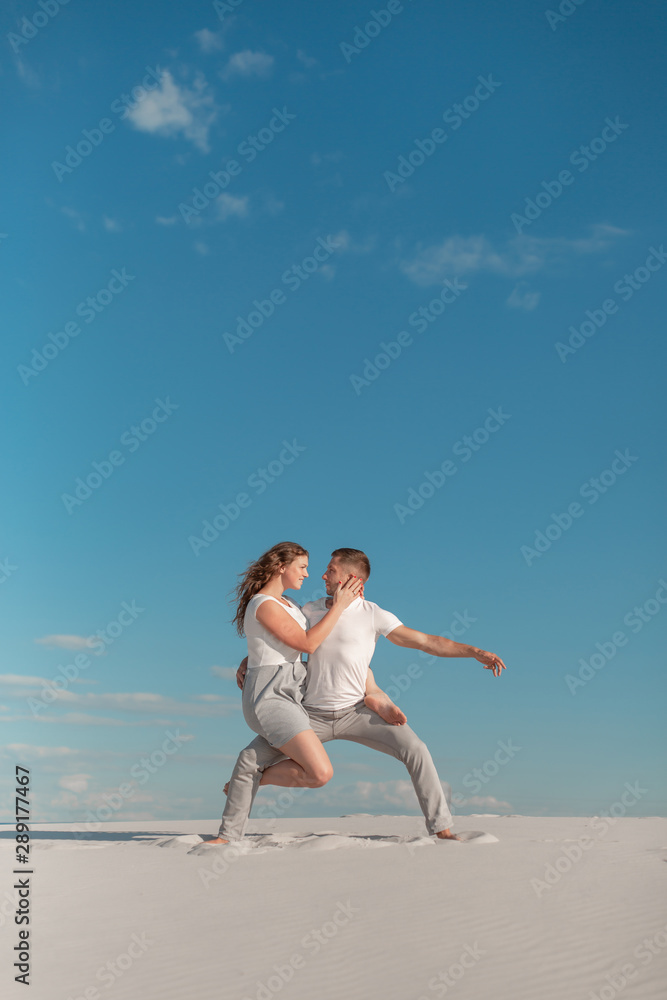 Romantic couple dancing in sand desert at blue sky background. Romantic couple dancing in sand desert at blue sky background.