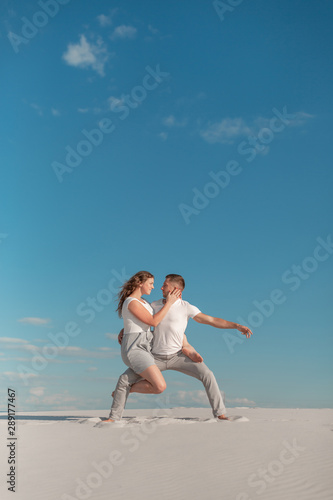 Fototapeta Naklejka Na Ścianę i Meble -  Romantic couple dancing in sand desert at blue sky background.