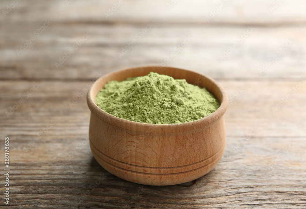 Bowl of wheat grass powder on wooden table Bowl of wheat grass powder on wooden table