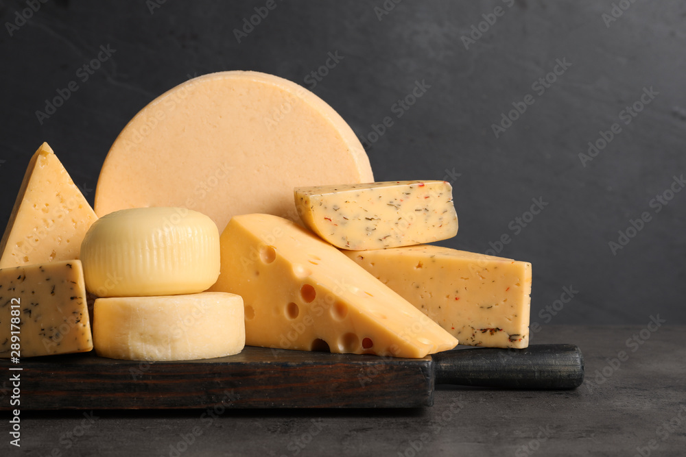 Fototapeta premium Wooden board with different sorts of cheese on grey table