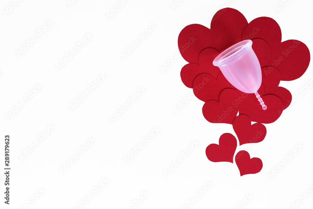 Menstrual cup from medicinal silicone is eco friendly solution for period intimate hygiene. Flat lay on red hearts, on white background with copy space. Menstrual cup from medicinal silicone is eco friendly solution for period intimate hygiene. Flat lay on red hearts, on white background with copy space.