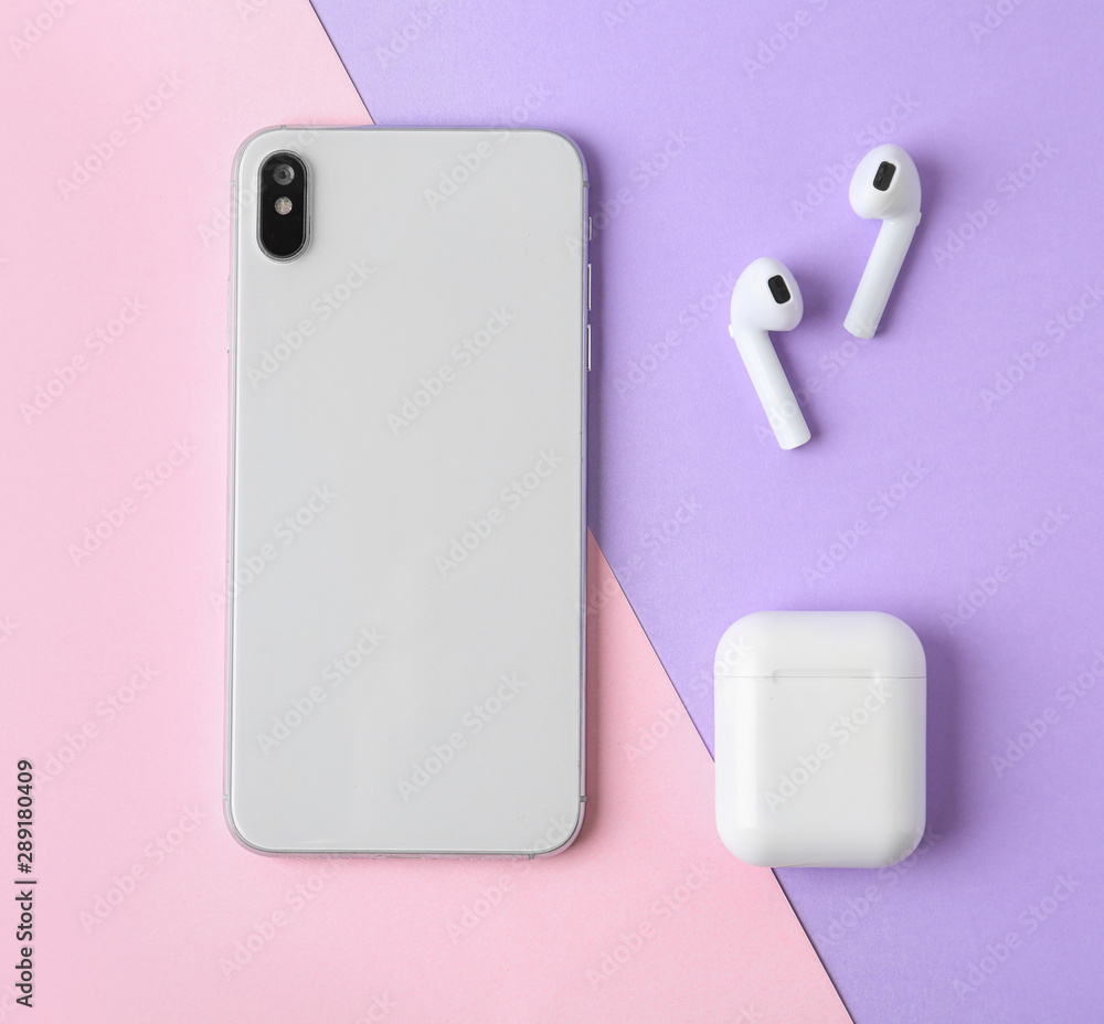 Wireless earphones, mobile phone and charging case on color background, flat lay Wireless earphones, mobile phone and charging case on color background, flat lay