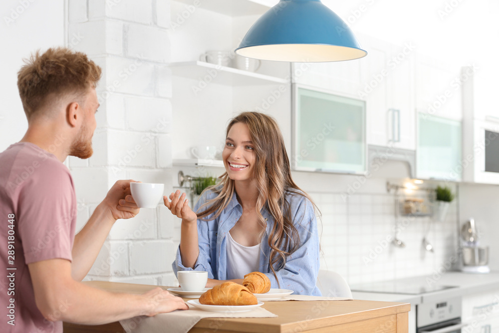 Happy young couple having breakfast at table in kitchen Happy young couple having breakfast at table in kitchen