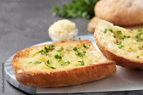 Slices of delicious toasted bread with garlic and herbs on grey table, closeup