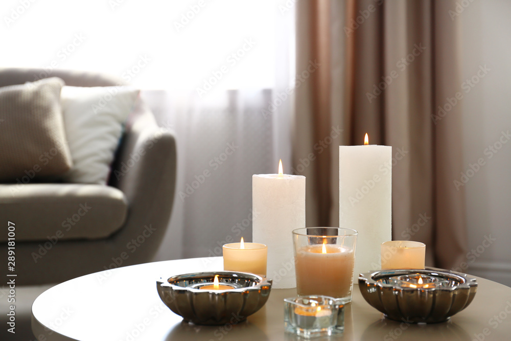 Burning decorative candles on table in room