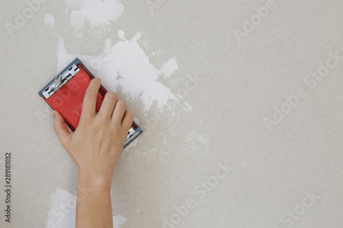 Process of sanding wall with a sanding block after skim coating. Preparation before painting. Renovation house concept. photo