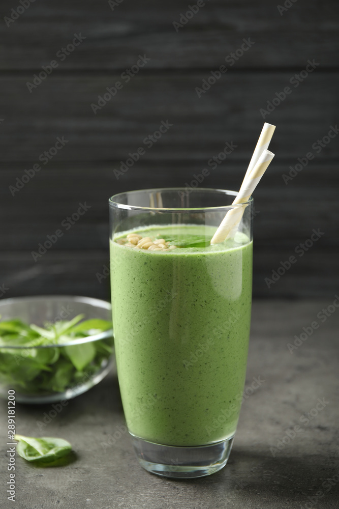 Glass of healthy green smoothie with fresh spinach on grey table Glass of healthy green smoothie with fresh spinach on grey table