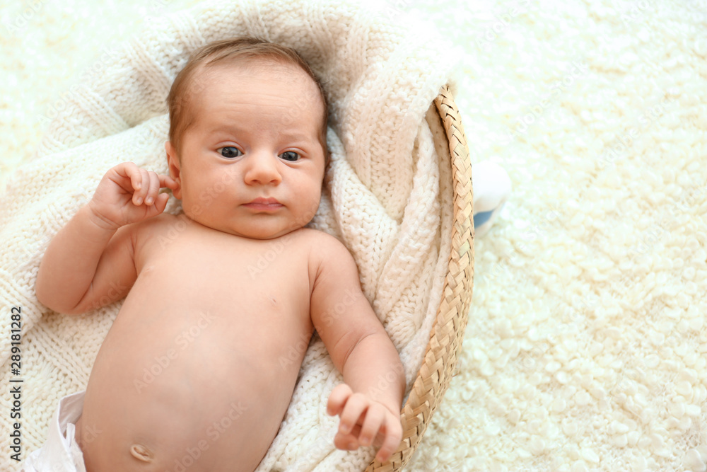 Cute little baby lying on knitted plaid in cradle, top view. Space for text Cute little baby lying on knitted plaid in cradle, top view. Space for text