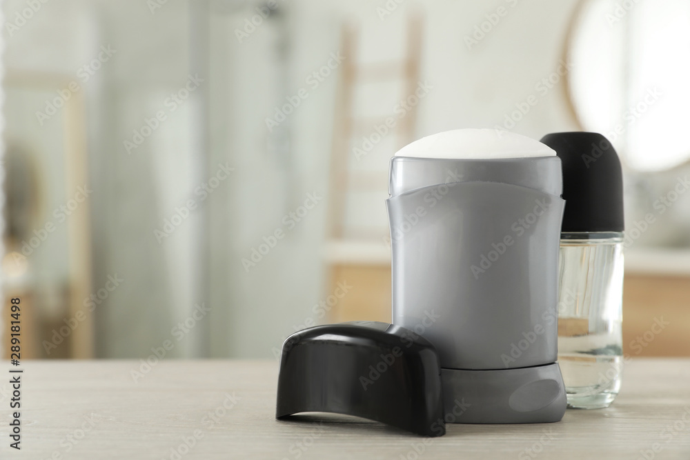 Male deodorants on wooden table in bathroom. Space for text