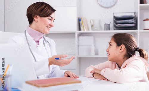 Doctor fills patient card for girl