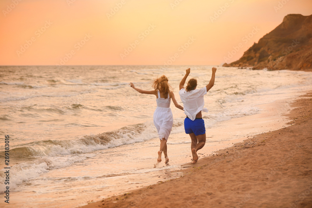 Young couple having fun on beach at sunset
