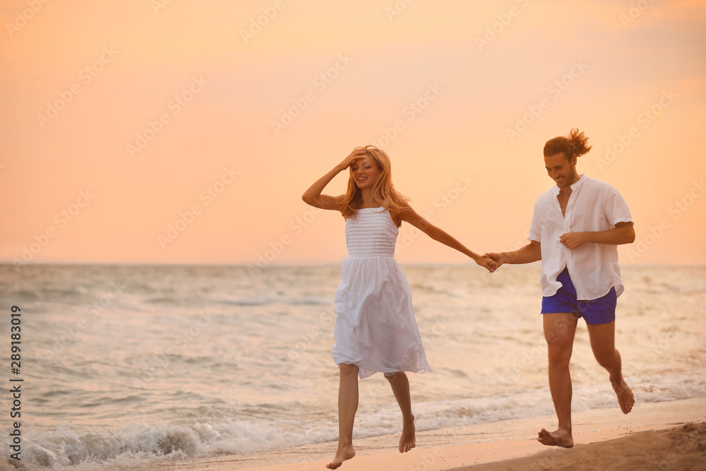 Young couple having fun on beach at sunset