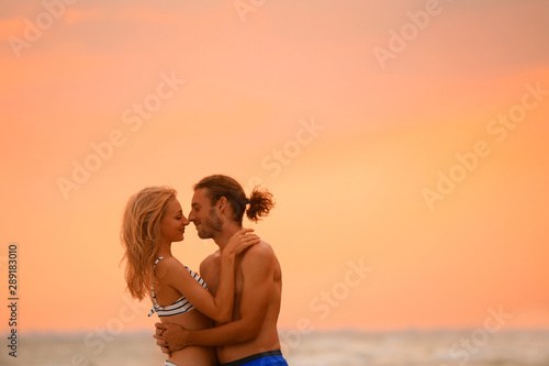 Young woman in bikini and her boyfriend on beach at sunset. Lovely couple © New Africa