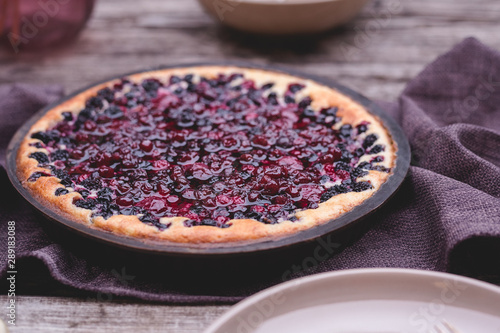 Berry pie with cherry, currant, blackberry, blueberry on wooden table in rustic style . Homemade cheesecake.