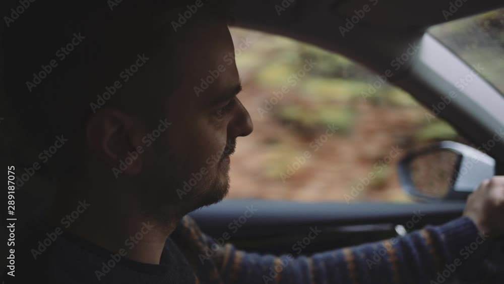 Man Driving a Car. SLOW MOTION. Portrait of a young handsome male driver navigating through fall countryside and forest on a rainy day. Man Driving a Car. SLOW MOTION. Portrait of a young handsome male driver navigating through fall countryside and forest on a rainy day.