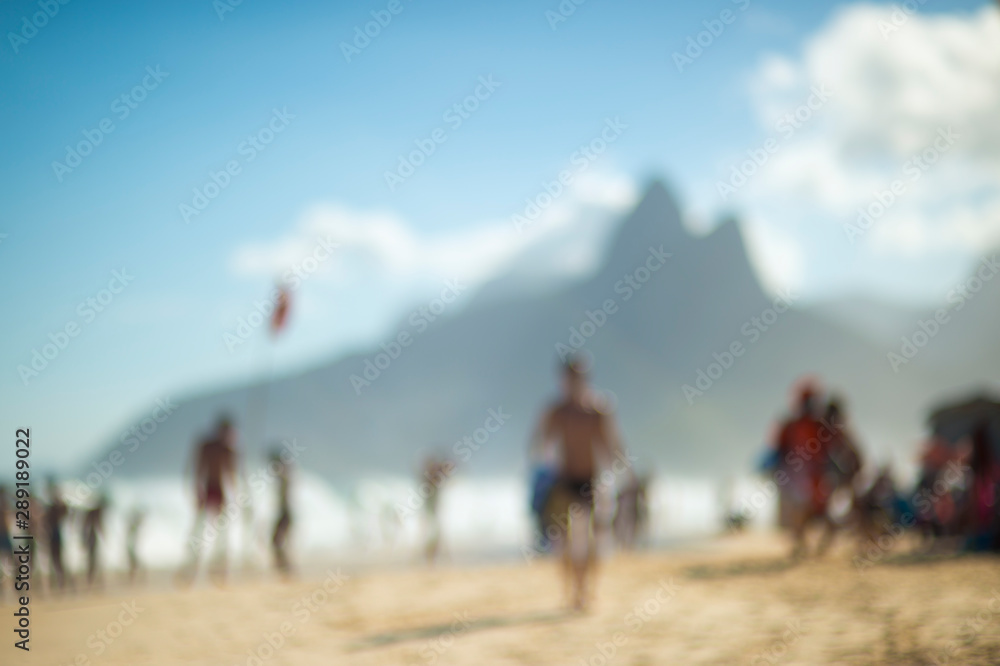 Abstract defocus view of a busy day on Ipanema Beach in Rio de Janeiro, Brazil with the looming silhouette of Two Brothers Mountain