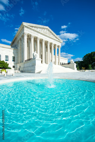 Bright scenic view of the Neoclassical columned entrance portico to the US Supreme Court building in Washington DC with a foreground fountain