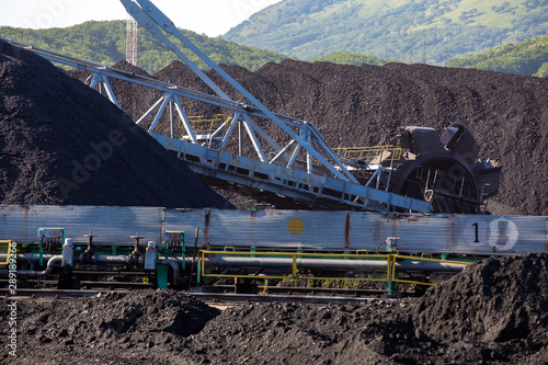 Stacker-reclaimer during loading and unloading of coal. Coal heaps at a marine coal terminal