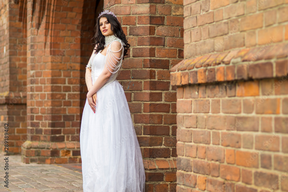 Fototapeta premium Portrait of Romantic Sensual Caucasian Bride With Crown And Necklace Posing Against Old Brick Wall Outdoos.