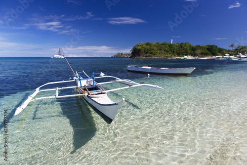Tropical landscape with  Filipino traditional banka fishing outrigger boat on a white sand beach, beautiful clear turquoise water. Malapascua island, Philippines.