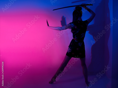 Barefoot female posing with samurai sword abstract light background 