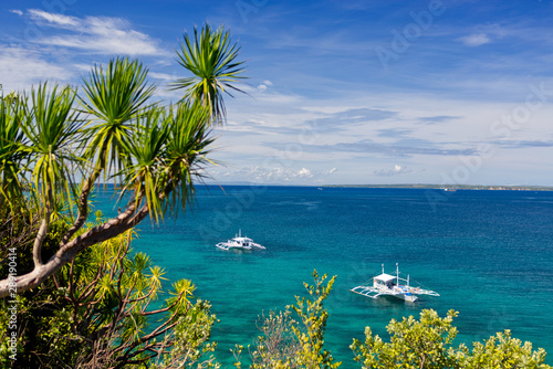 Tropical landscape with Filipino traditional banka fishing outrigger boat floating on a beautiful blue turquoise ocean, bright sunny day. Malapascua, Philippine.