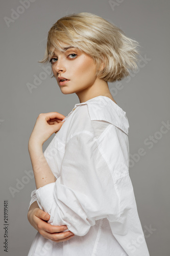 Portrait of beautiful blonde woman in white shirt and fashionable hair