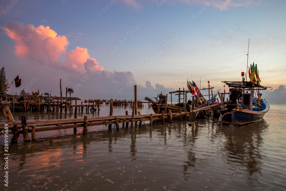 Fototapeta premium Panoramic wallpaper of the morning light scenery by the sea, with small fishing boats of the villagers landing, with blurred waves of sea, a beautiful way of life by the river community
