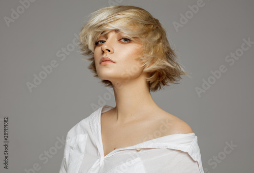 Portrait of beautiful blonde woman in white shirt and fashionable hairstyle
